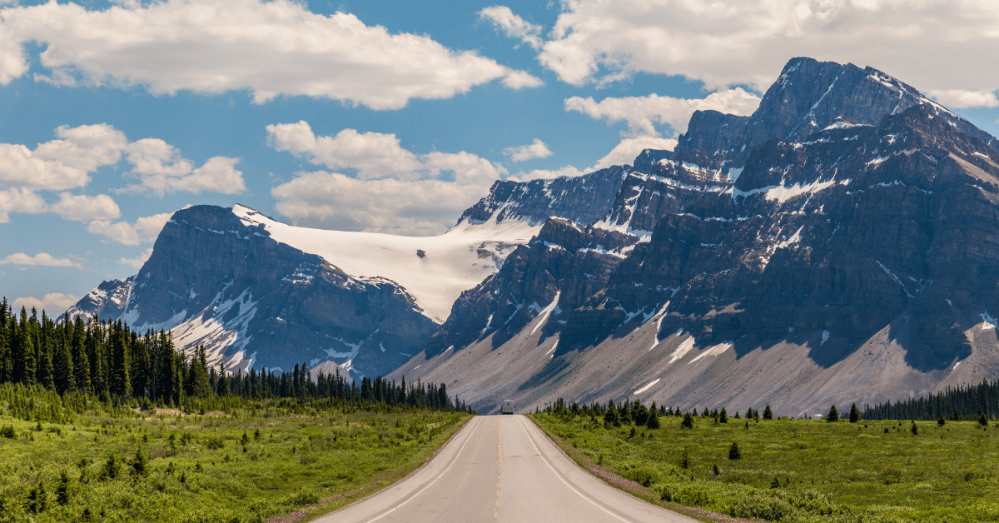 A view from the icefields parkway of the road and mountains with a large glacier in the background